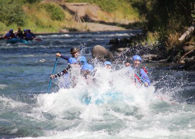 A group of rafters getting splashed while going through a rapid.
