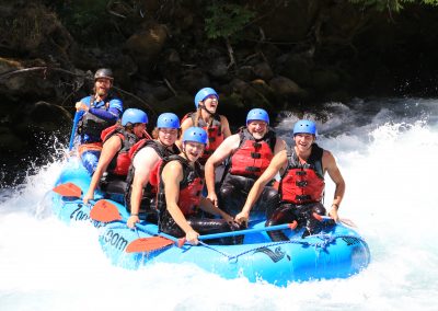 A group of young rafters smiling while paddling on the White Salmon middle gorge.