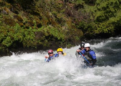 Four people in a raft being covered in water from the rapids.